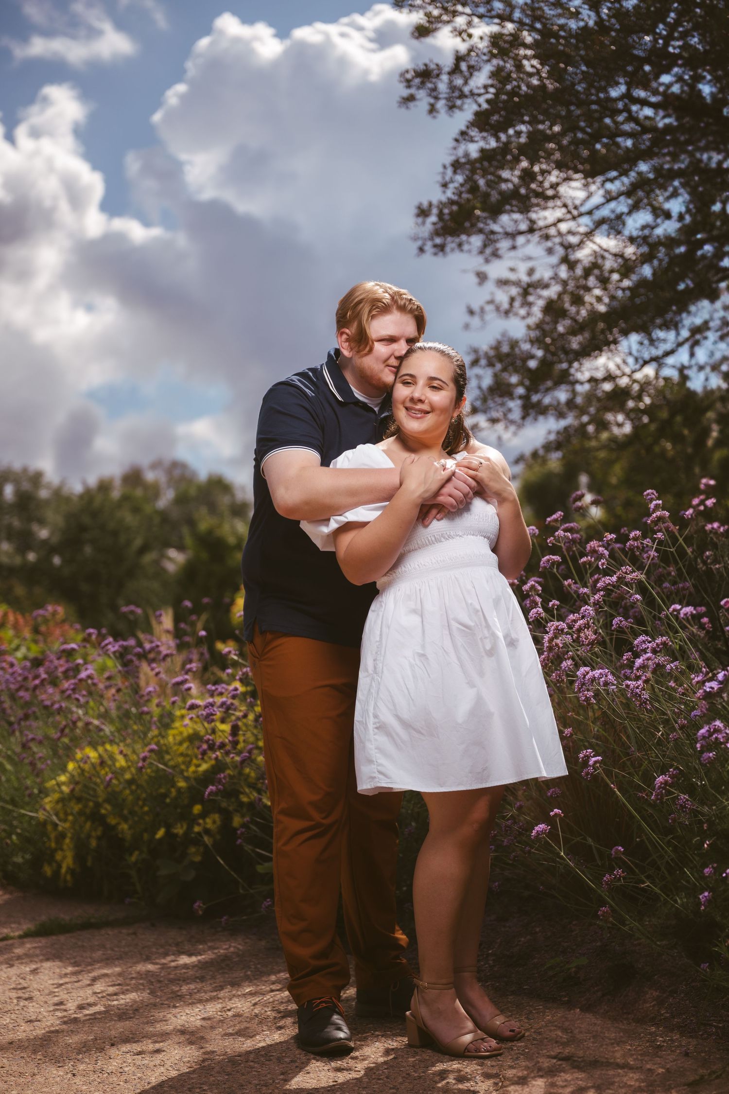 A couple sharing a tender moment among purple wildflowers in a garden setting.