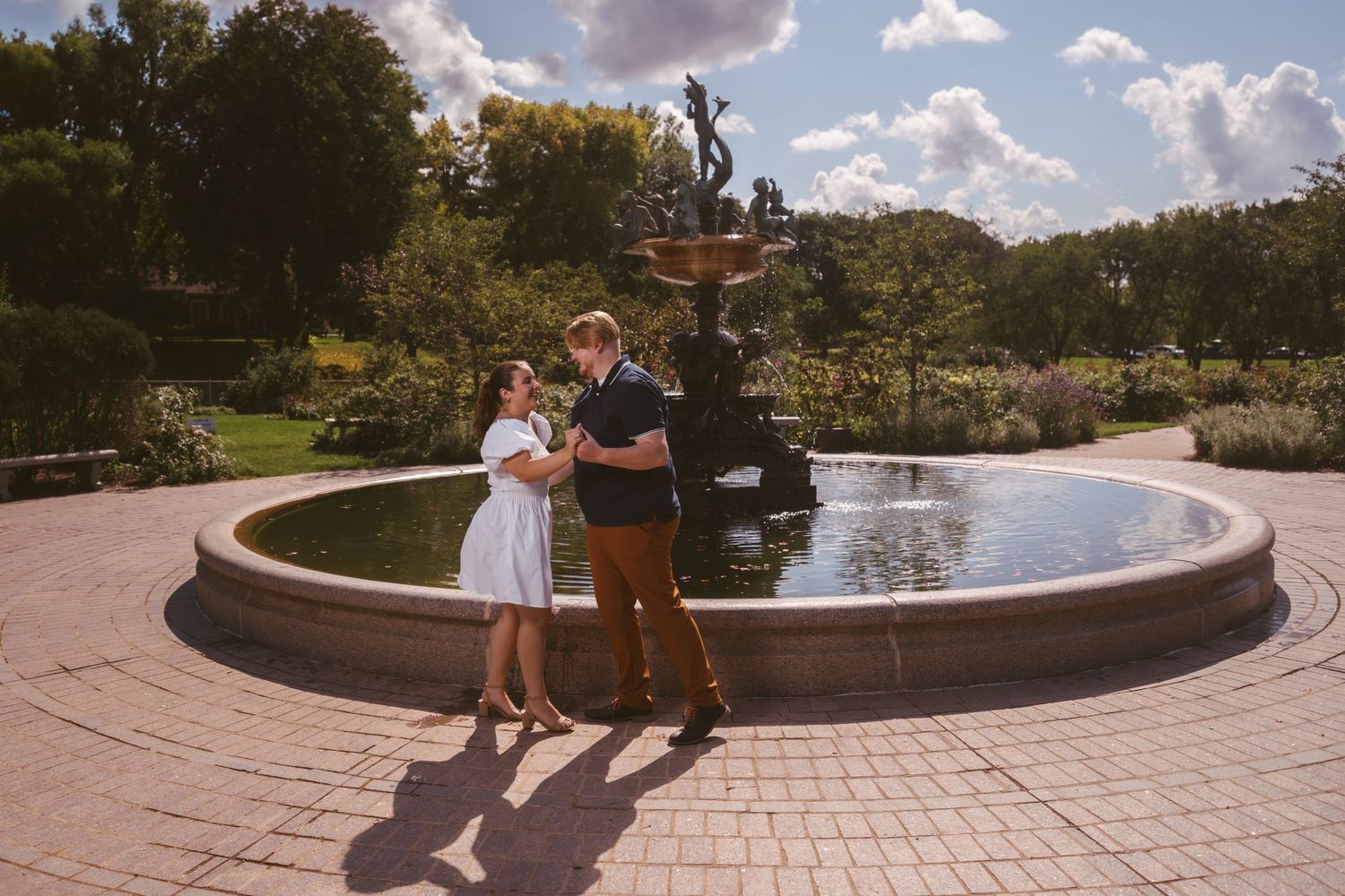 A couple poses together near a curved stone pathway in a landscaped garden.