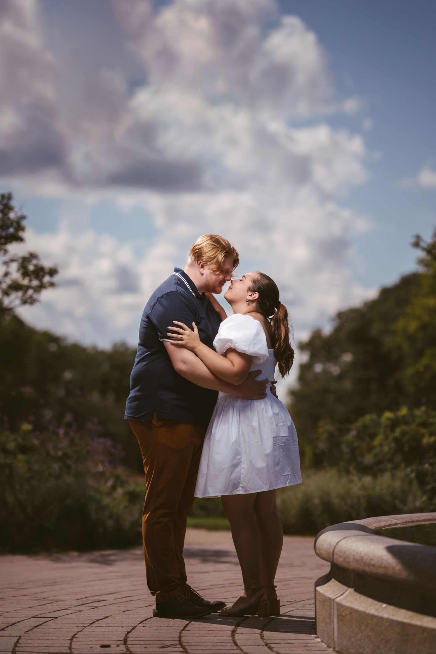 A romantic engagement photoshoot sequence showing a couple embracing against a cloudy sky backdrop.