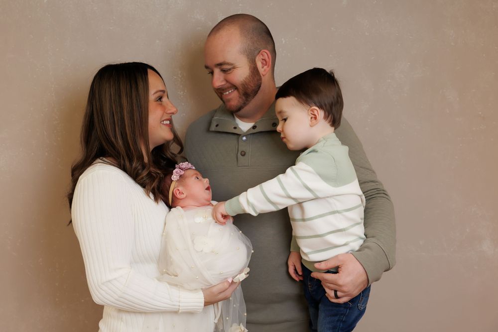 A sweet moment between family members as they share an intimate photo session against a brown backdrop.