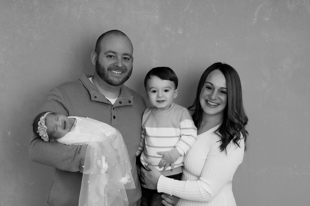 A heartwarming family portrait in black and white against a simple gray backdrop.