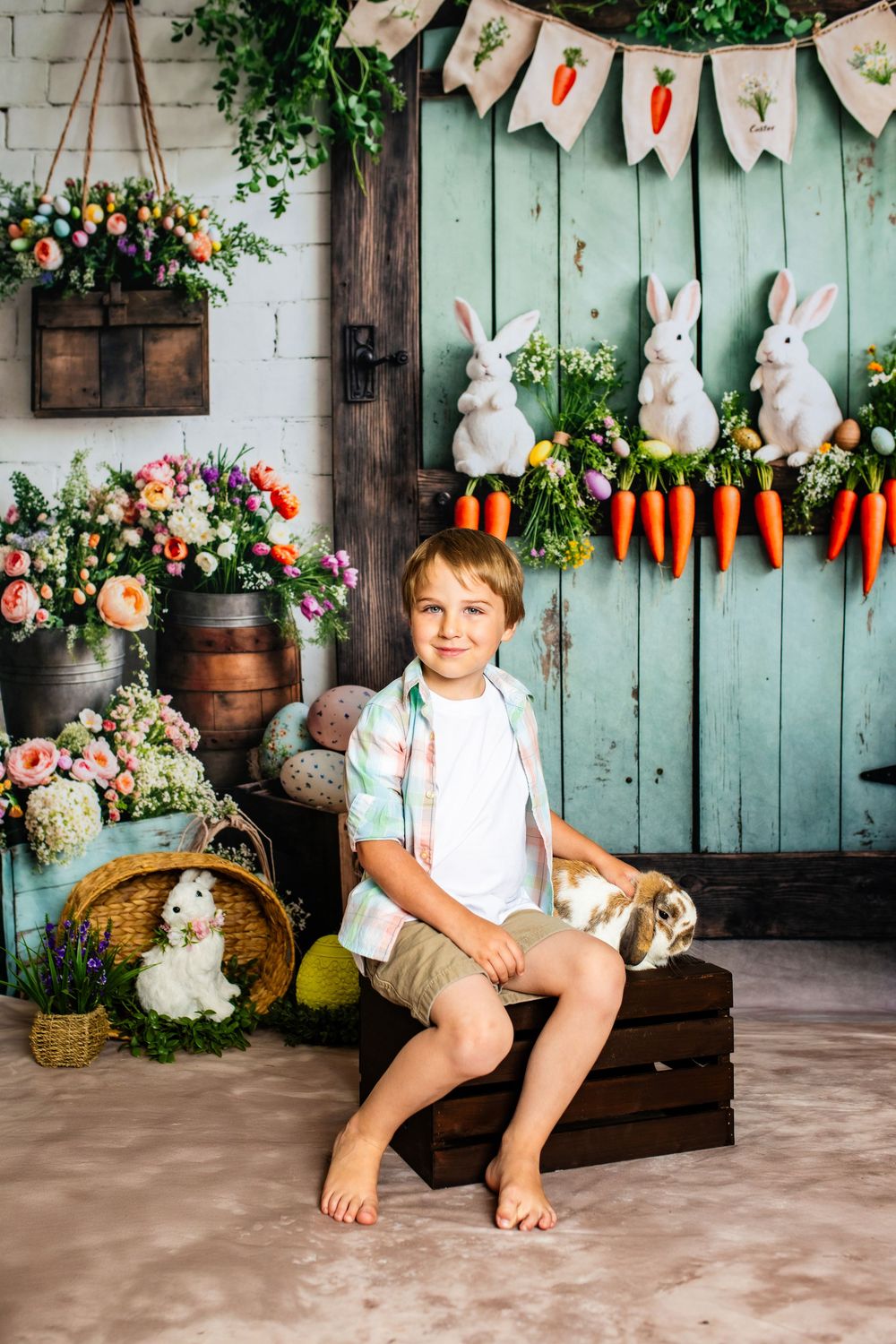 Spring photo setup with vintage pastel door, bunny decorations, floral arrangements and rustic wooden accents.
