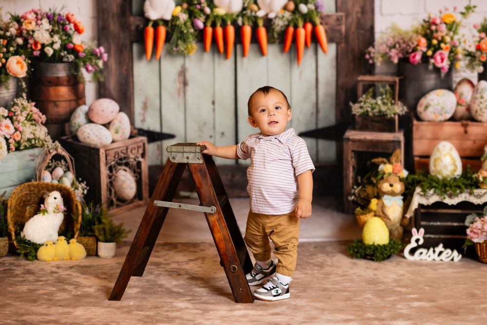 Easter themed photo scene with bunny decorations, hanging carrots, and a wooden ladder against rustic backdrop.