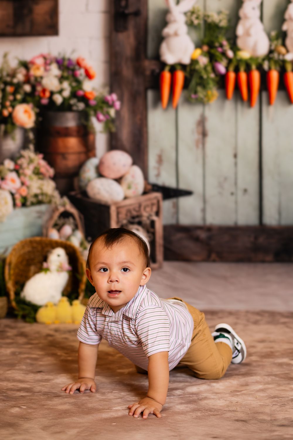 Easter themed indoor photo setup with carrots hanging on wall, flowers, and rustic decor elements.