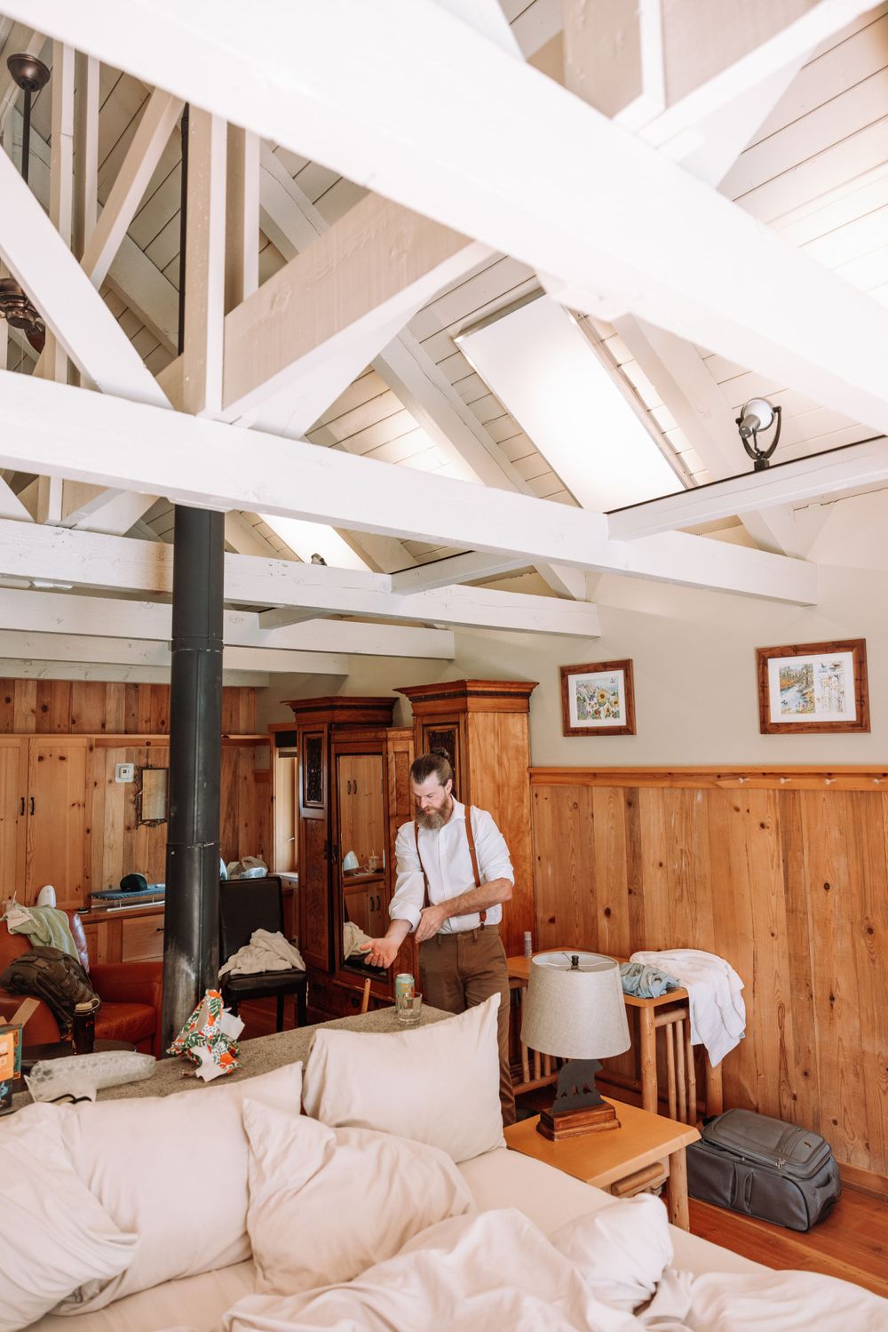 A rustic cabin interior with white beamed ceiling, wooden walls, and soft natural lighting.