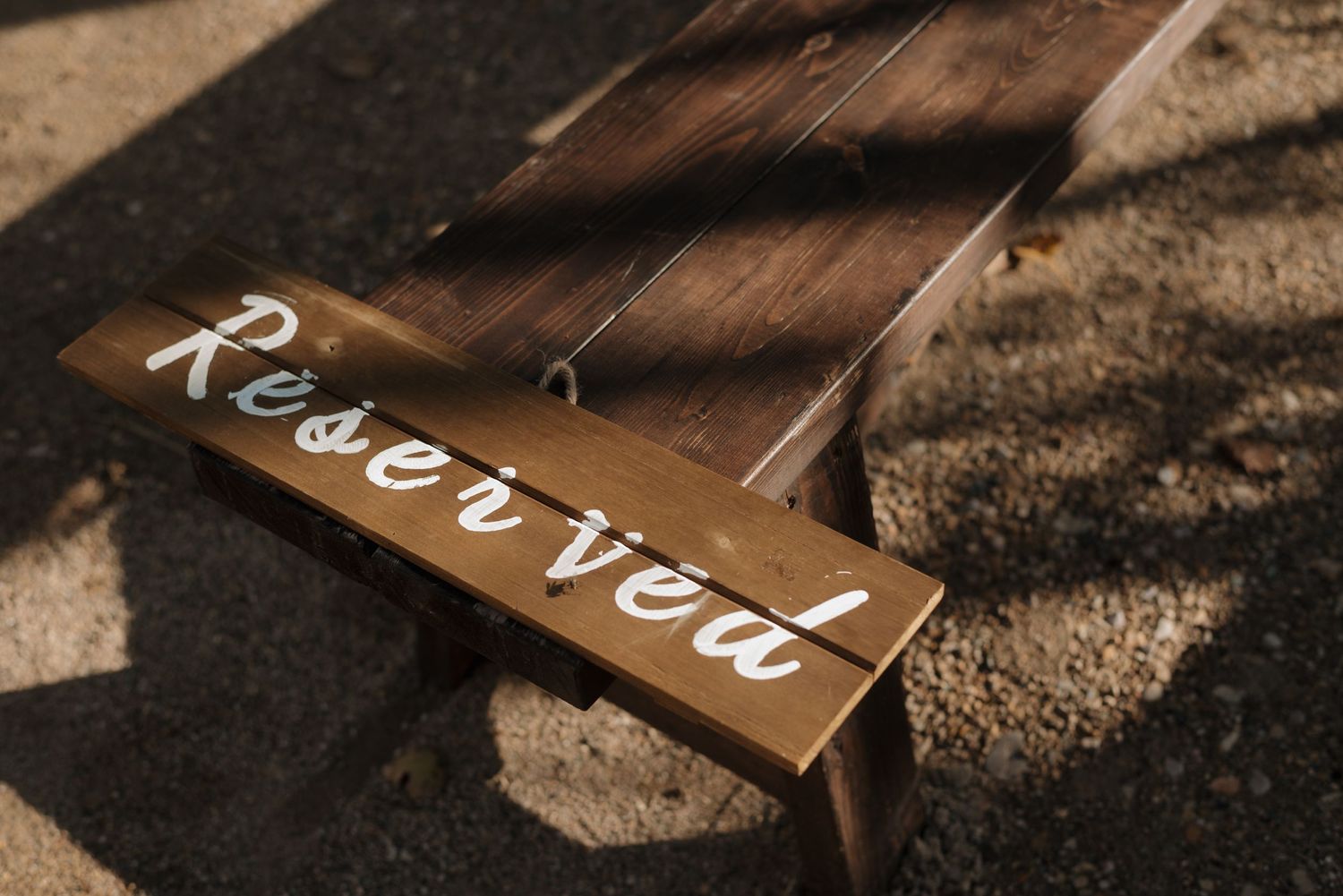 Rustic wooden sign with 'Reserved' written in white script lettering against dark wood background.
