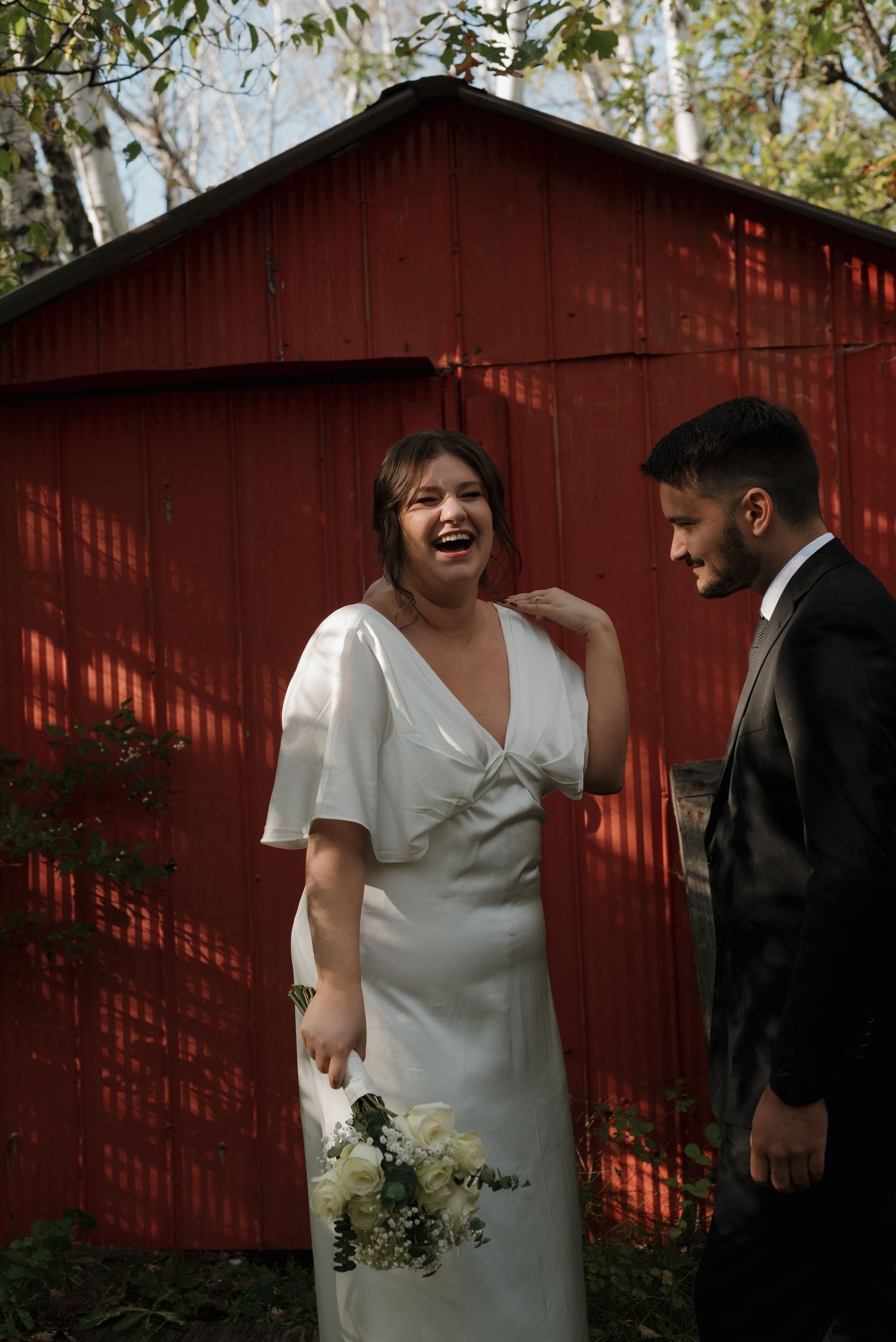 A joyful wedding moment captured in front of a rustic red barn.