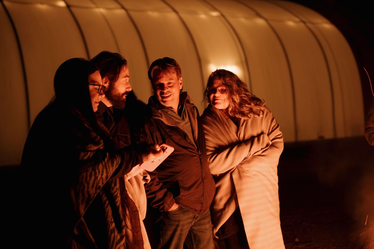 Group silhouette against warmly lit tent backdrop at nighttime.