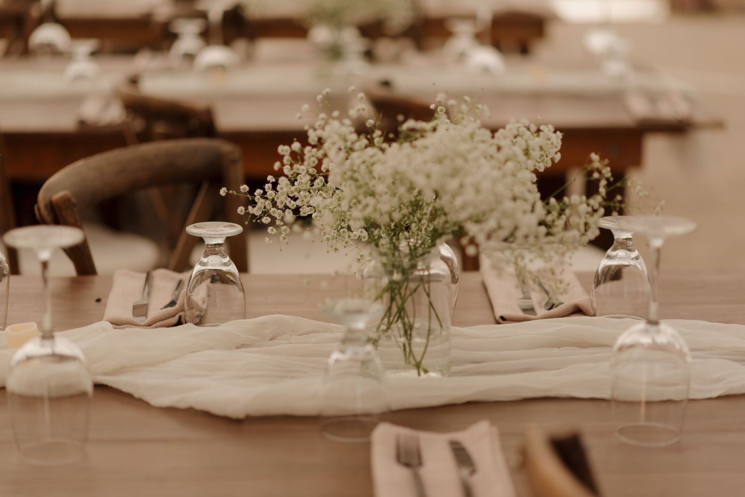 Elegant table setting with baby's breath centerpiece in glass vase and wine glasses at a wedding reception.