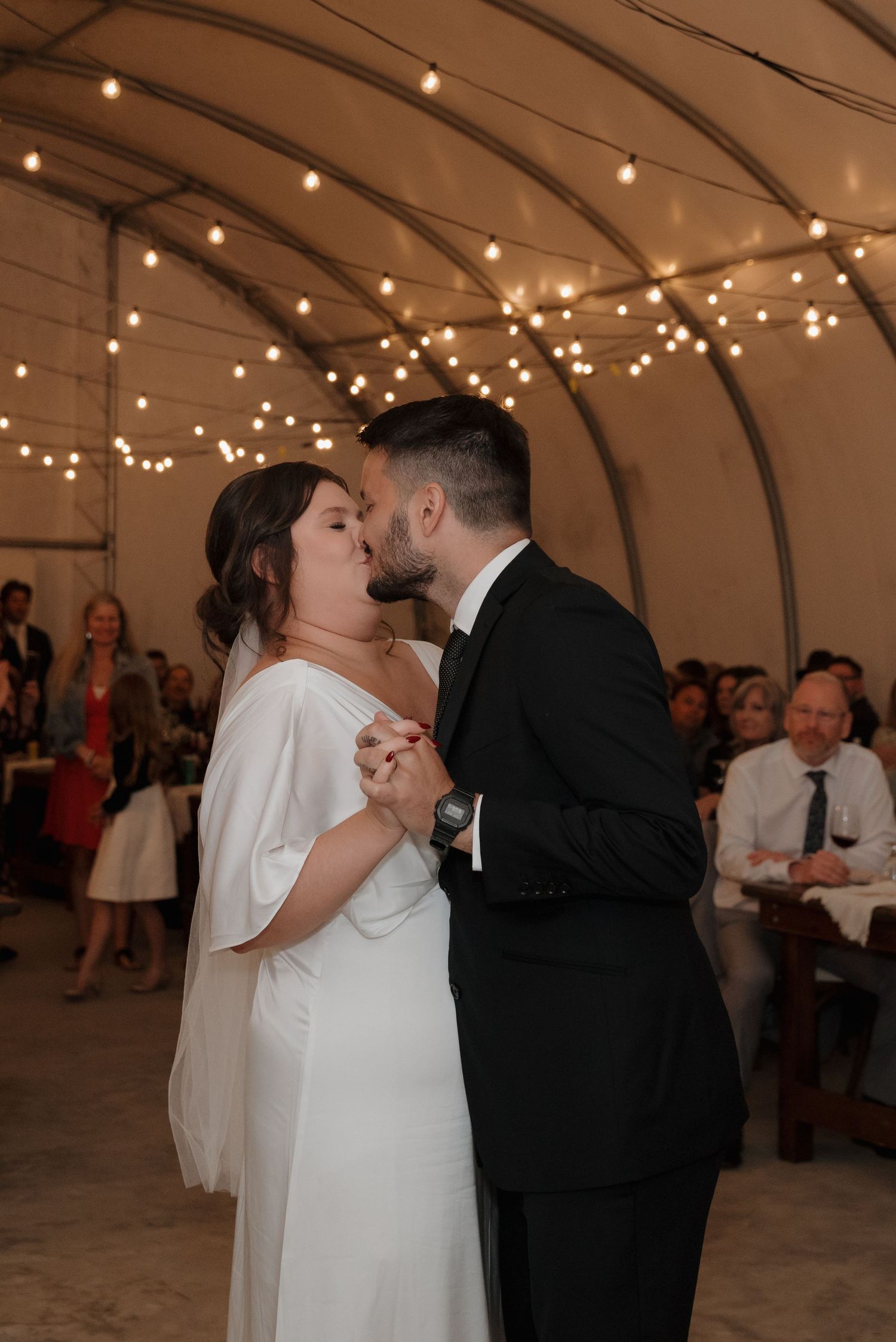 Wedding celebration in romantic tent venue with string lights and dance floor.
