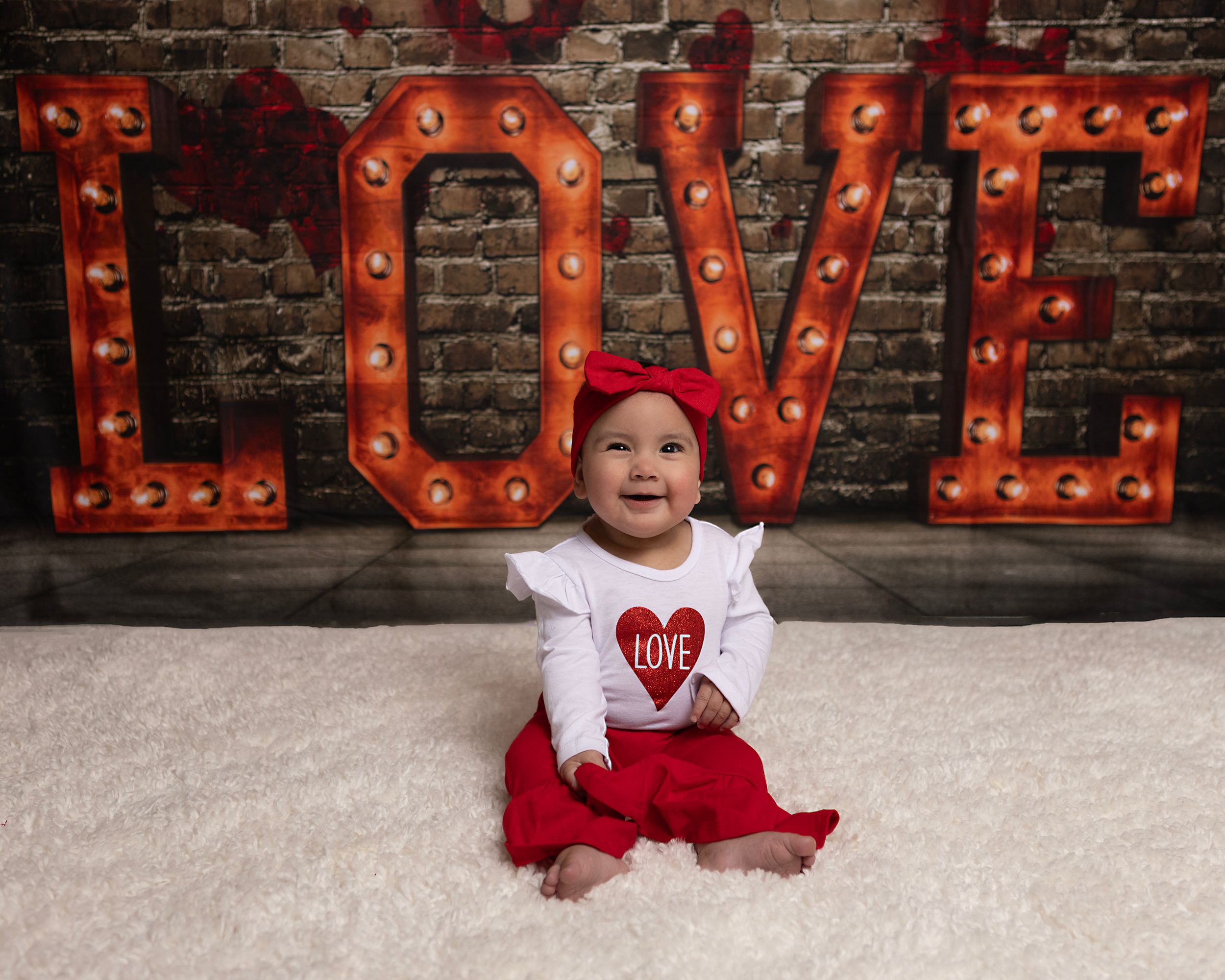 Valentine's themed photo setting with glowing LOVE sign and white floor covering.