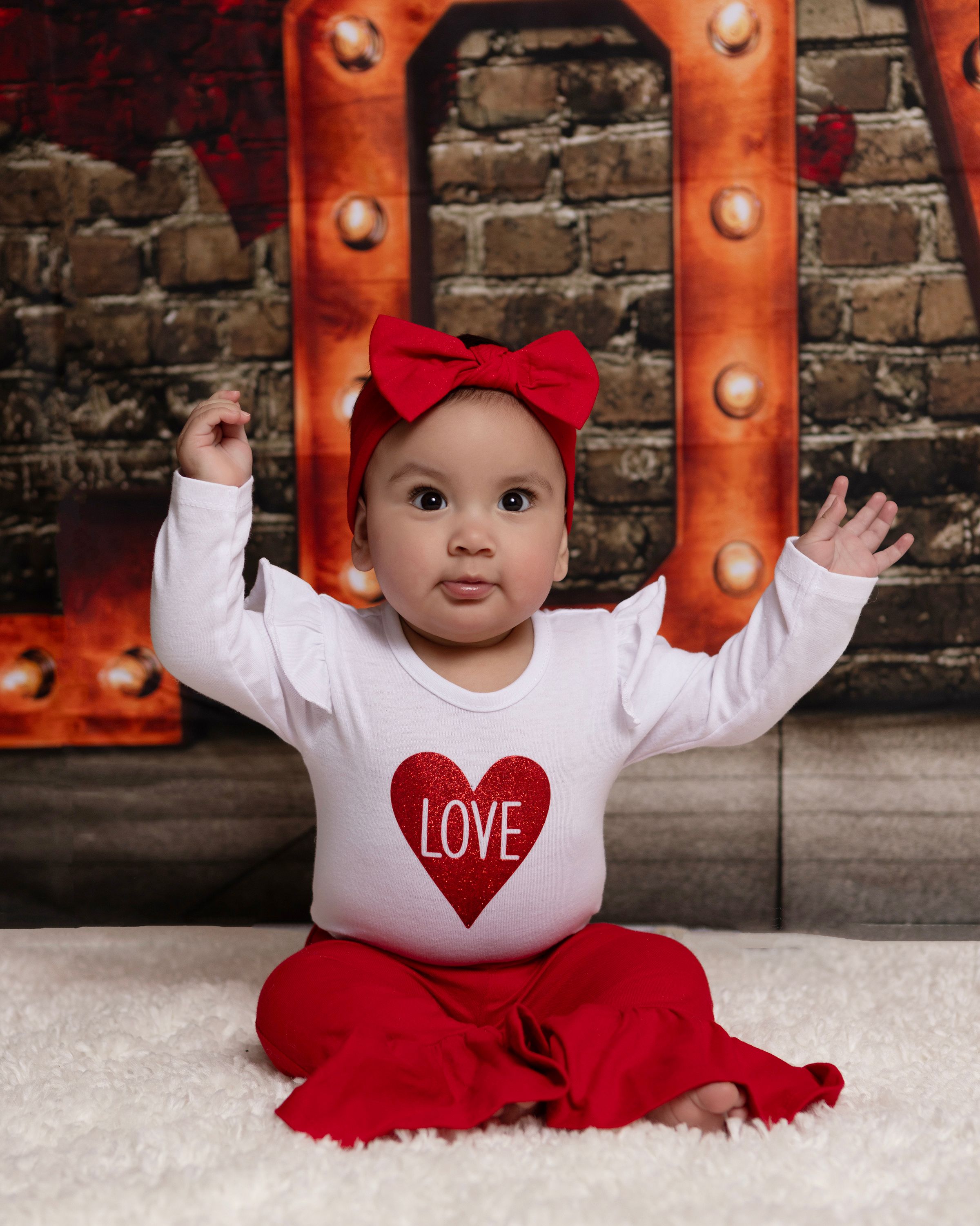 Valentine's themed photo with illuminated LOVE letters and white floor setting.