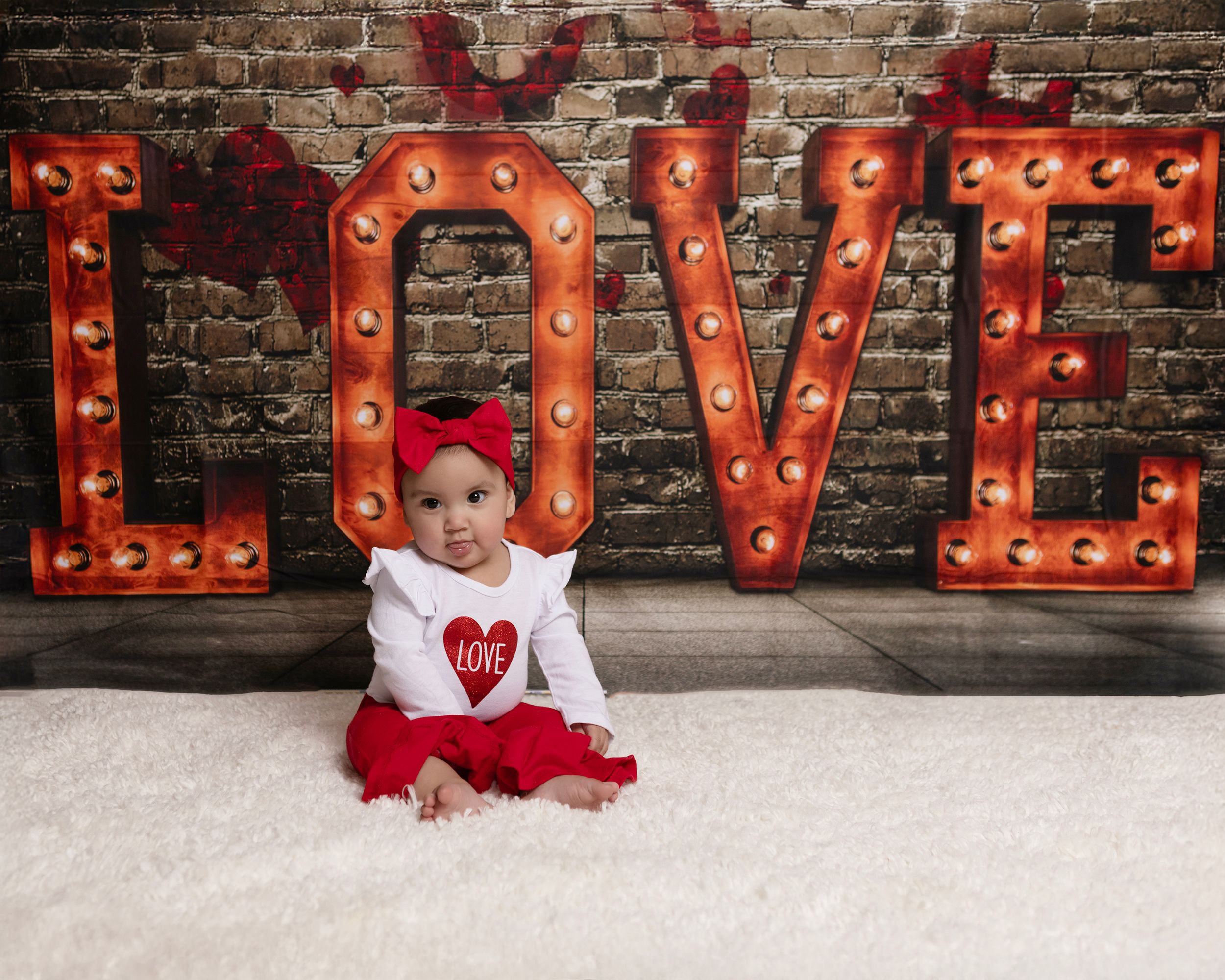 Red illuminated LOVE letters create romantic atmosphere against brick wall.
