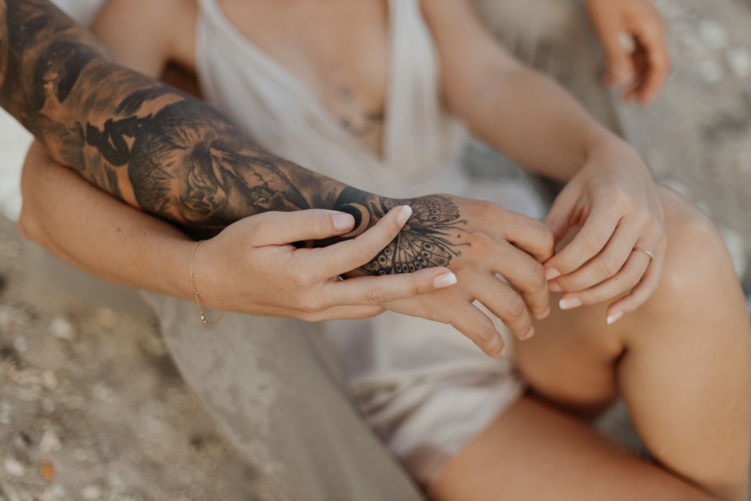 tatouage sur l'avant bras d'un couple assis sur la plage