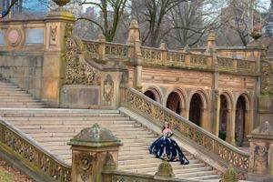 Grand ornate staircase with elaborate stone archways and railings at Bethesda Terrace in Central Park during winter.