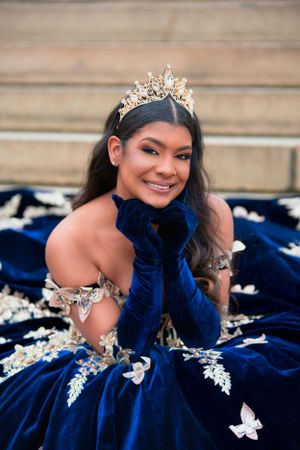Elegant royal blue velvet ball gown with silver butterfly appliques and crystal crown for a special occasion.