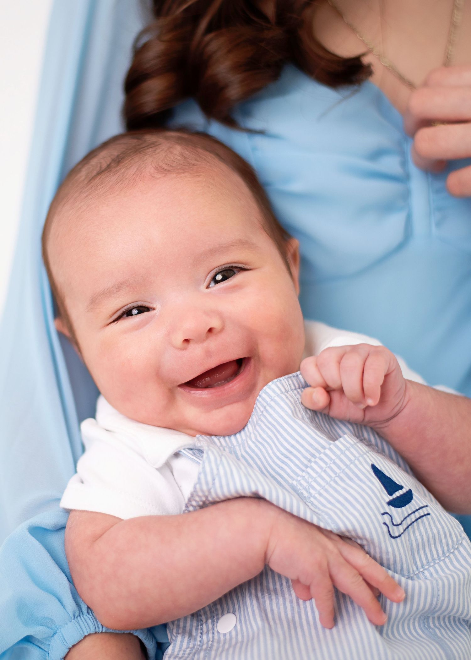 Happy baby wearing nautical outfit smiles brightly.