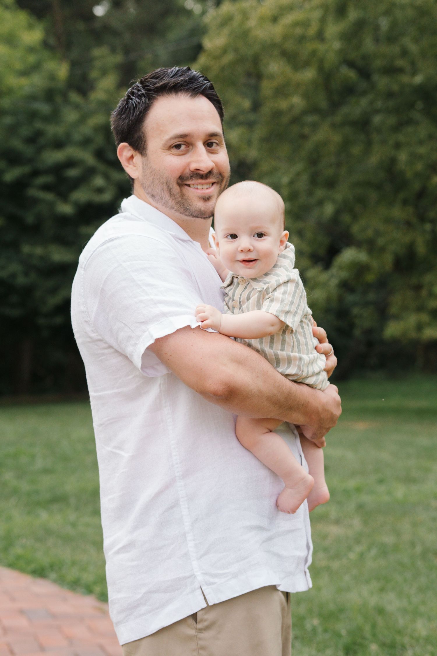 A heartwarming outdoor portrait of a dad holding a smiling baby at Barclay Farmstead, perfect for family photography in Cherry Hill, NJ.