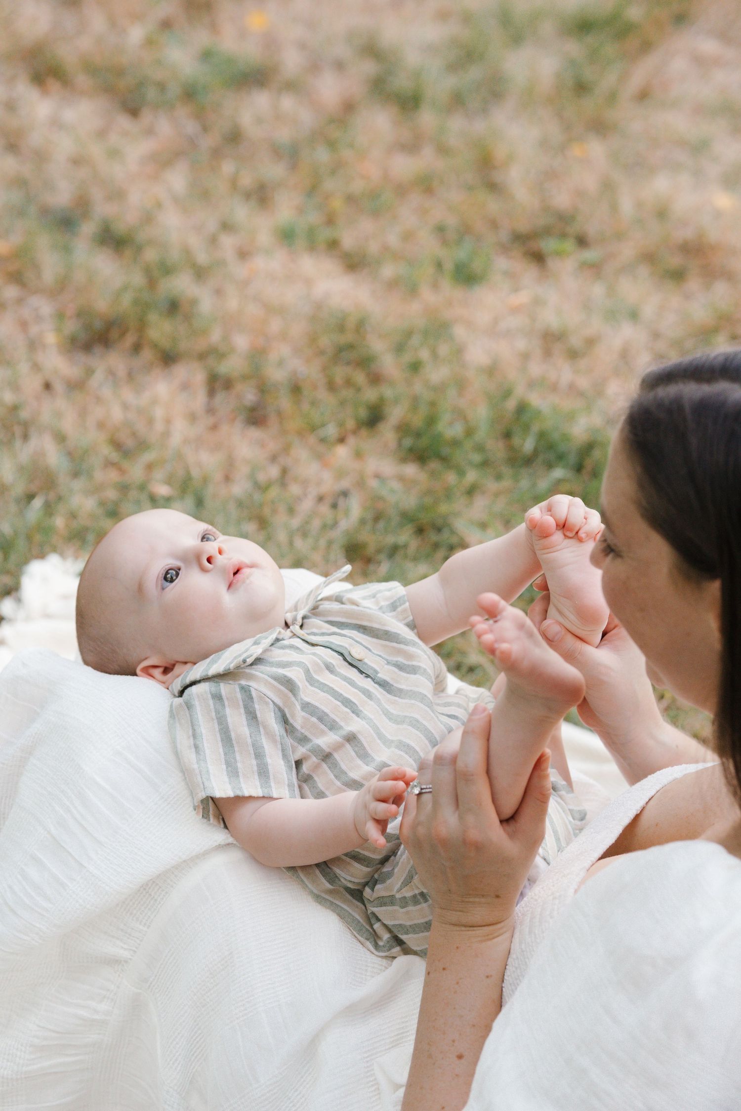 Mother holding her baby in her lap as he looks up at the sky, photographed at Barclay Farmstead in Cherry Hill.