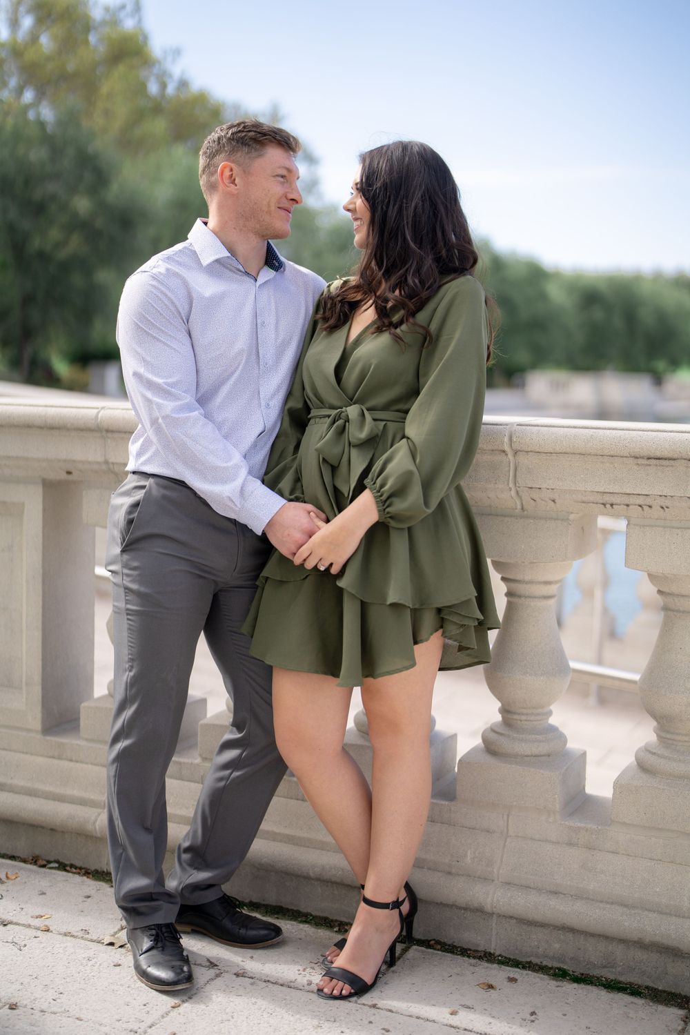A happy couple shares an intimate moment while posing on a classical stone balcony.