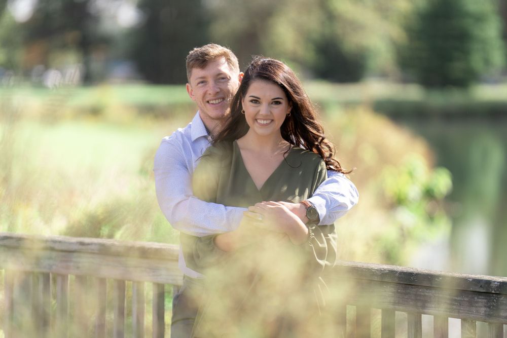 Sweet embrace captured in soft focus with natural landscape and pond in background.