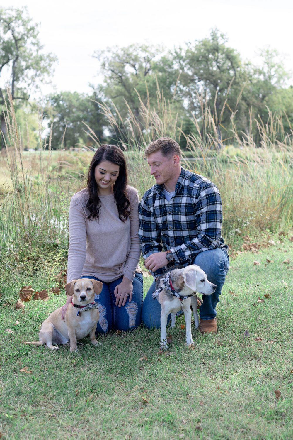 Casual outdoor portrait with couple and their two dogs against natural landscape.