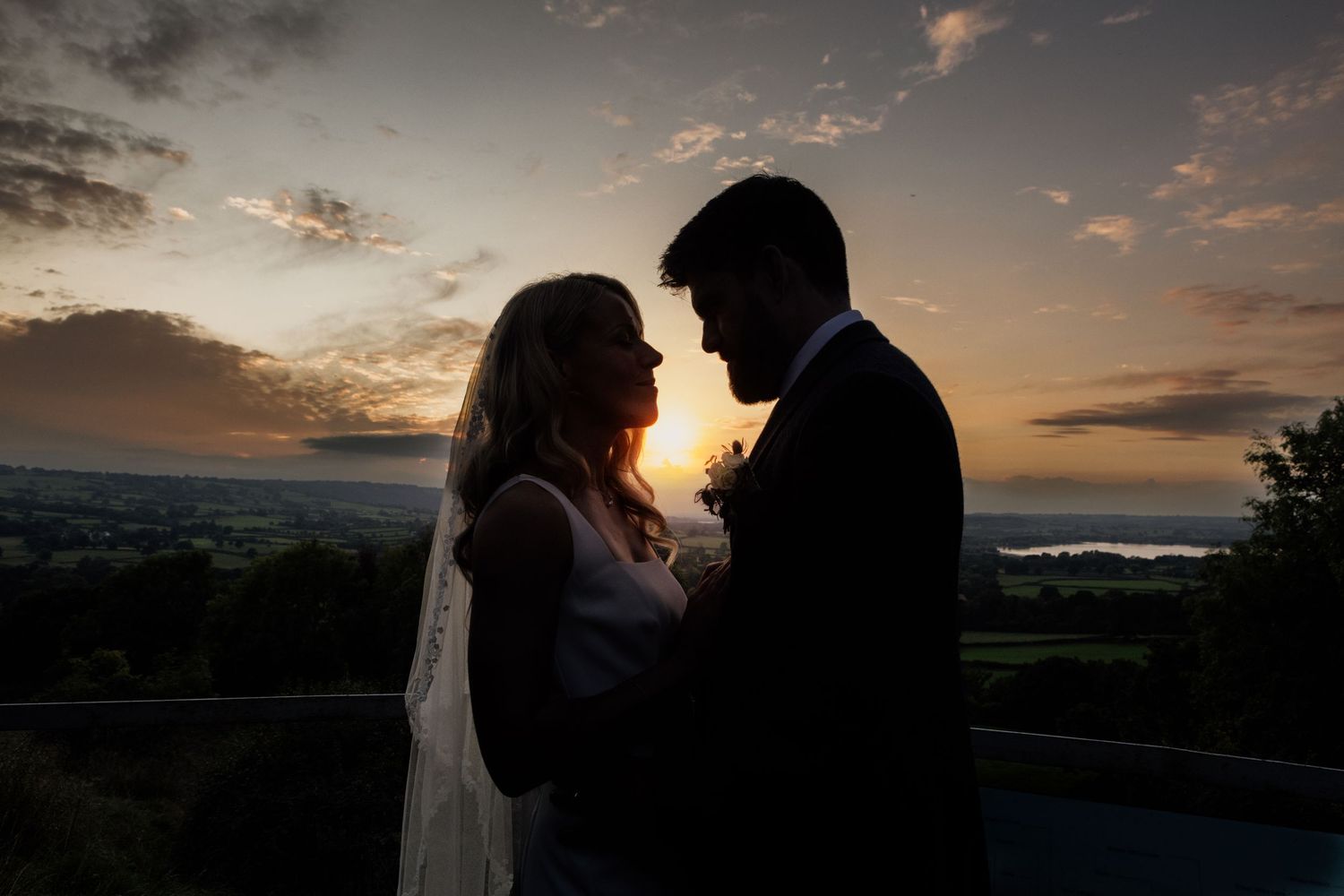 A silhouetted couple shares an intimate moment against a dramatic sunset sky.