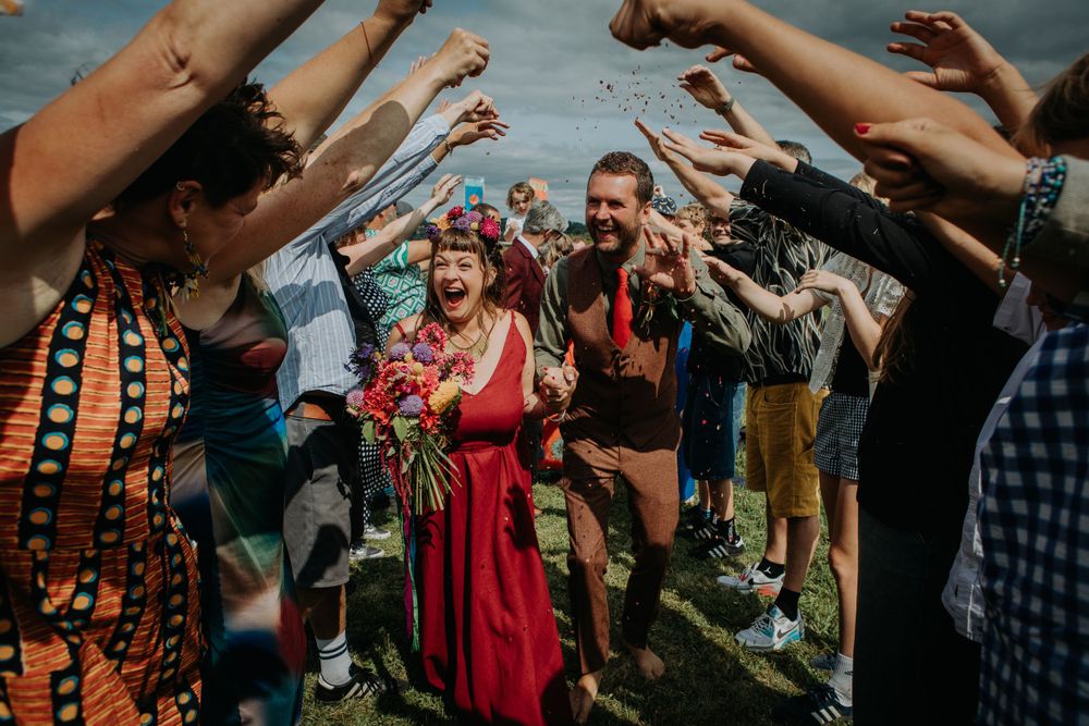 Wedding guests create a tunnel of raised arms for celebrating newlyweds.