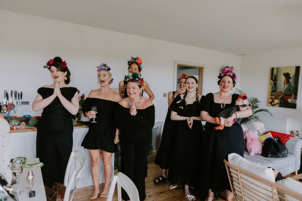Bridesmaids in black dresses pose playfully while getting ready for a wedding.
