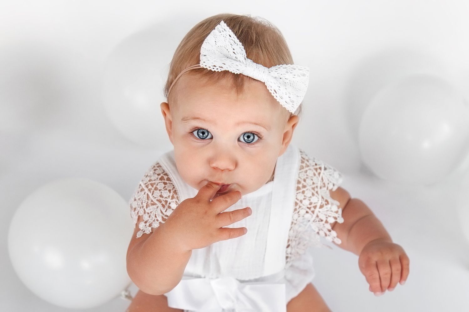 Baby Girl with big blue eyes, eating cake off fingers