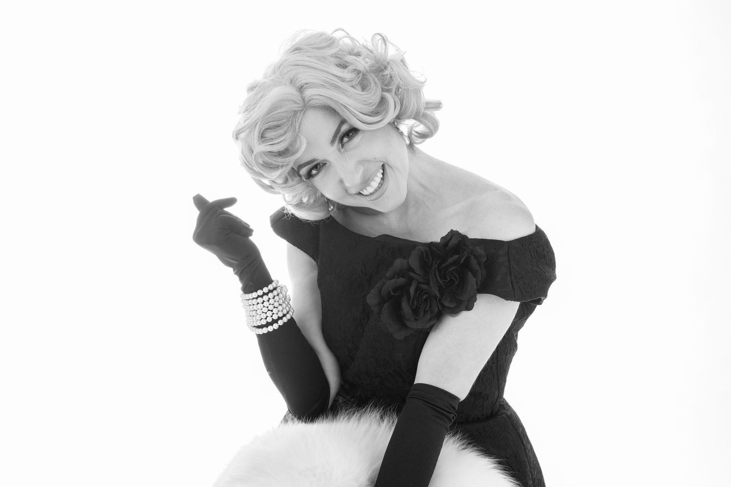 Elegant black and white portrait of a figure in glamorous evening attire with long gloves and curled platinum hair.