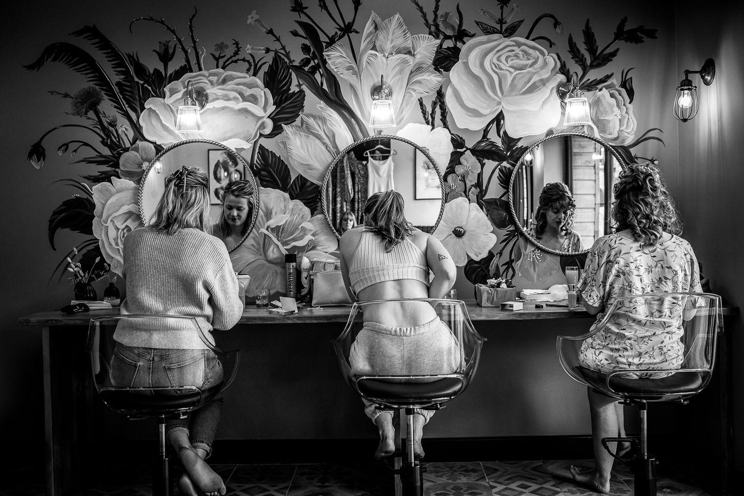 A black and white photo of three people seated at mirrors at Gellifawr Woodland Retreat