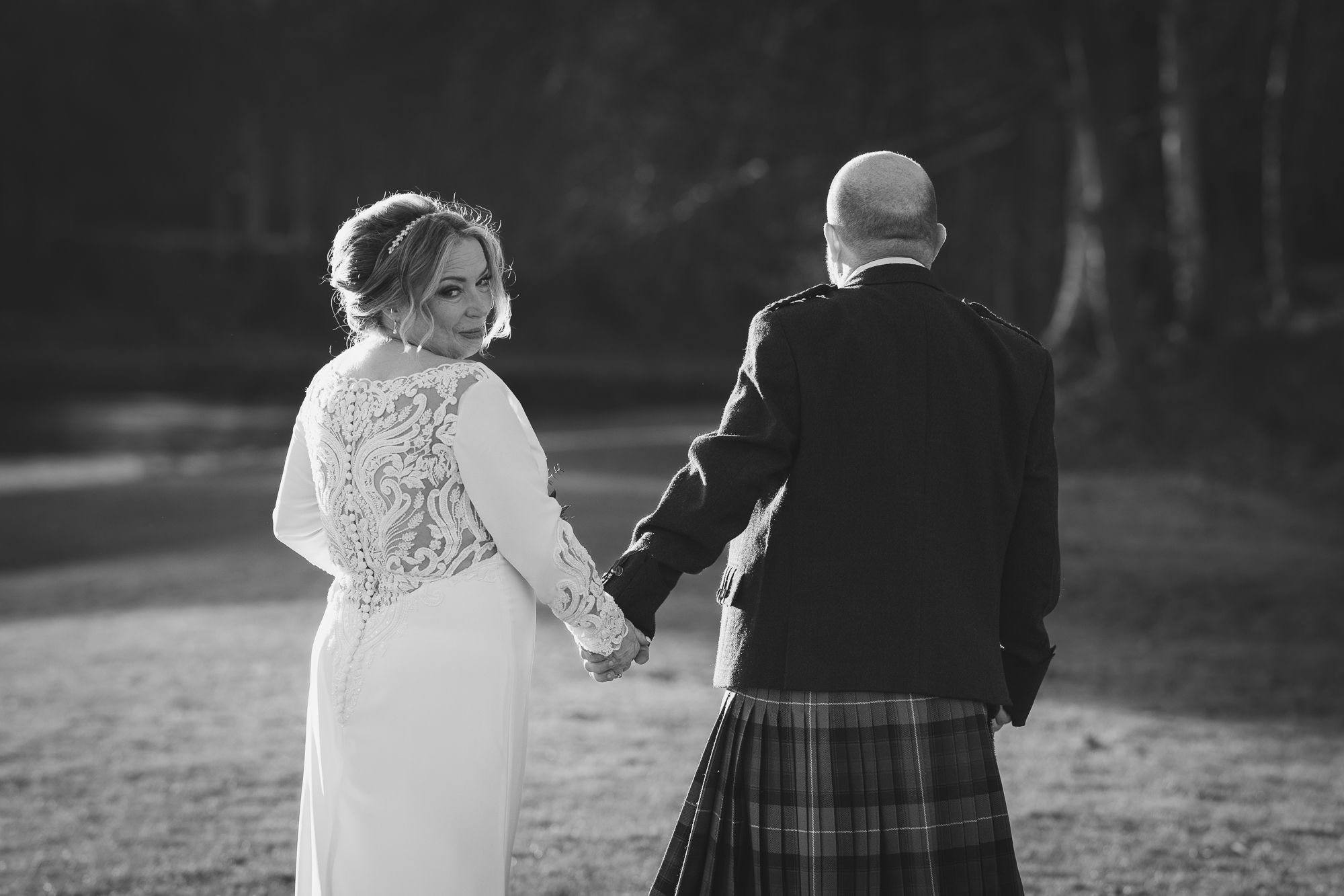 bride and groom walking with bride looking back