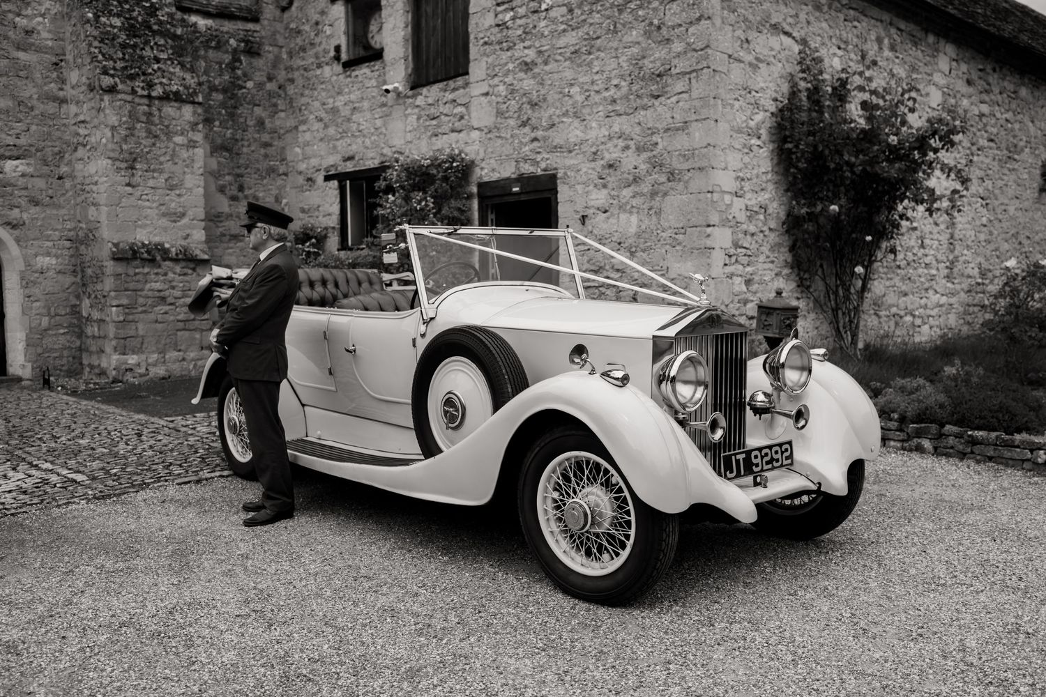 Classic vintage Rolls Royce car parked outside historic stone building.
