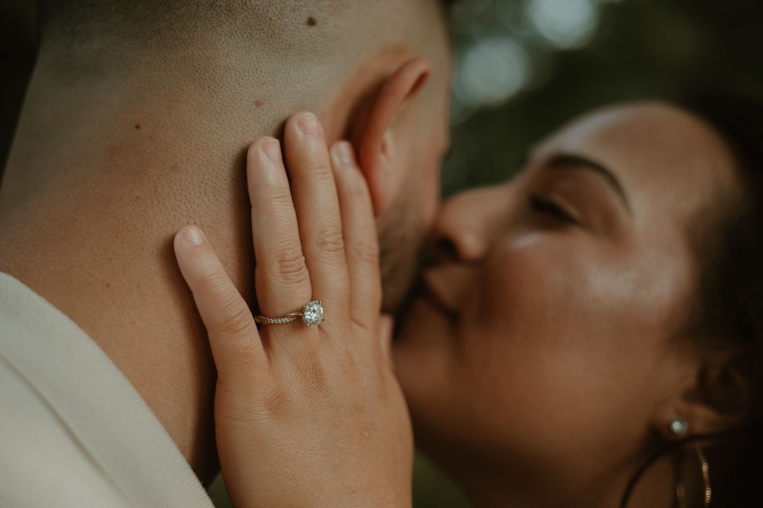 Woman grasping man's face, showing off engagement ring