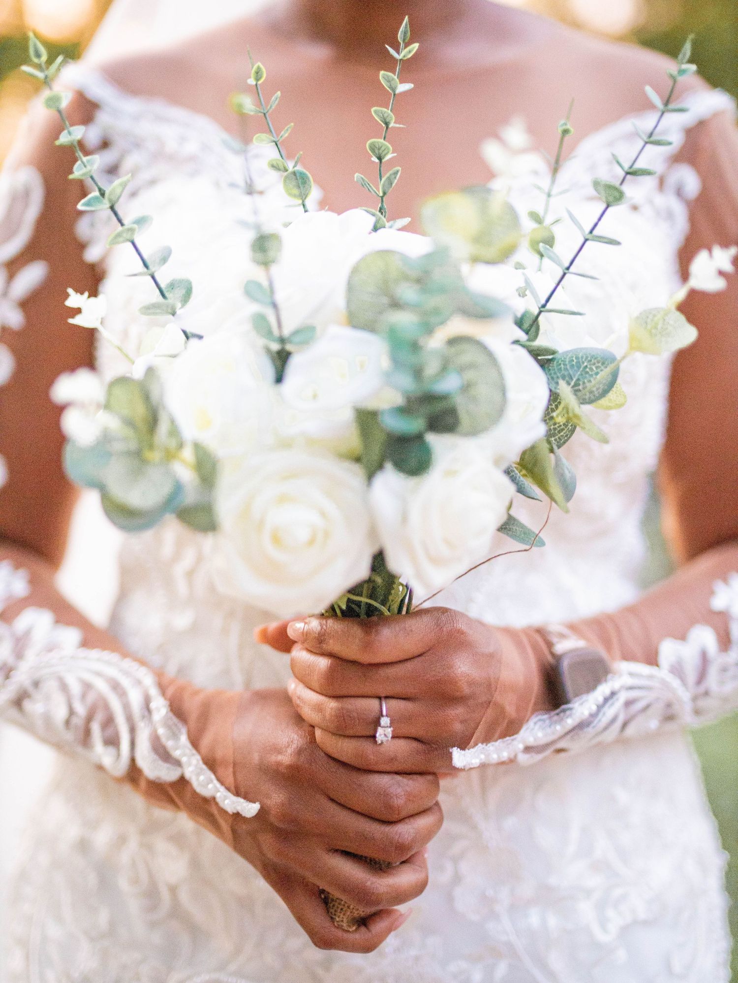 Bridal hands holding an elegant white and green floral bouquet with eucalyptus.