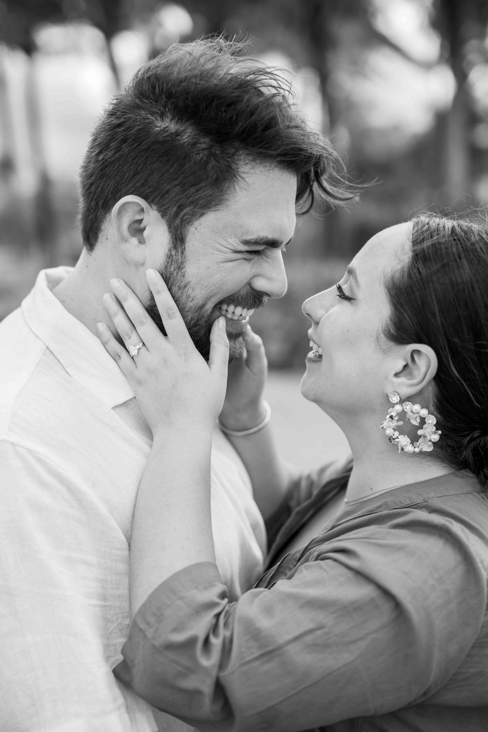 An intimate black and white portrait of a couple sharing a tender moment outdoors.