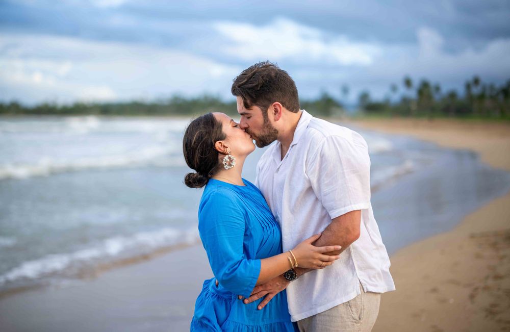 A romantic couple embraces on a beautiful beach with ocean waves in the background.