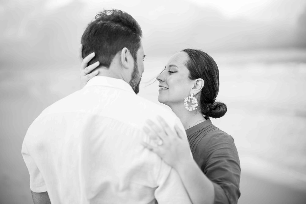 Black and white intimate portrait of a couple sharing a romantic moment by the ocean.