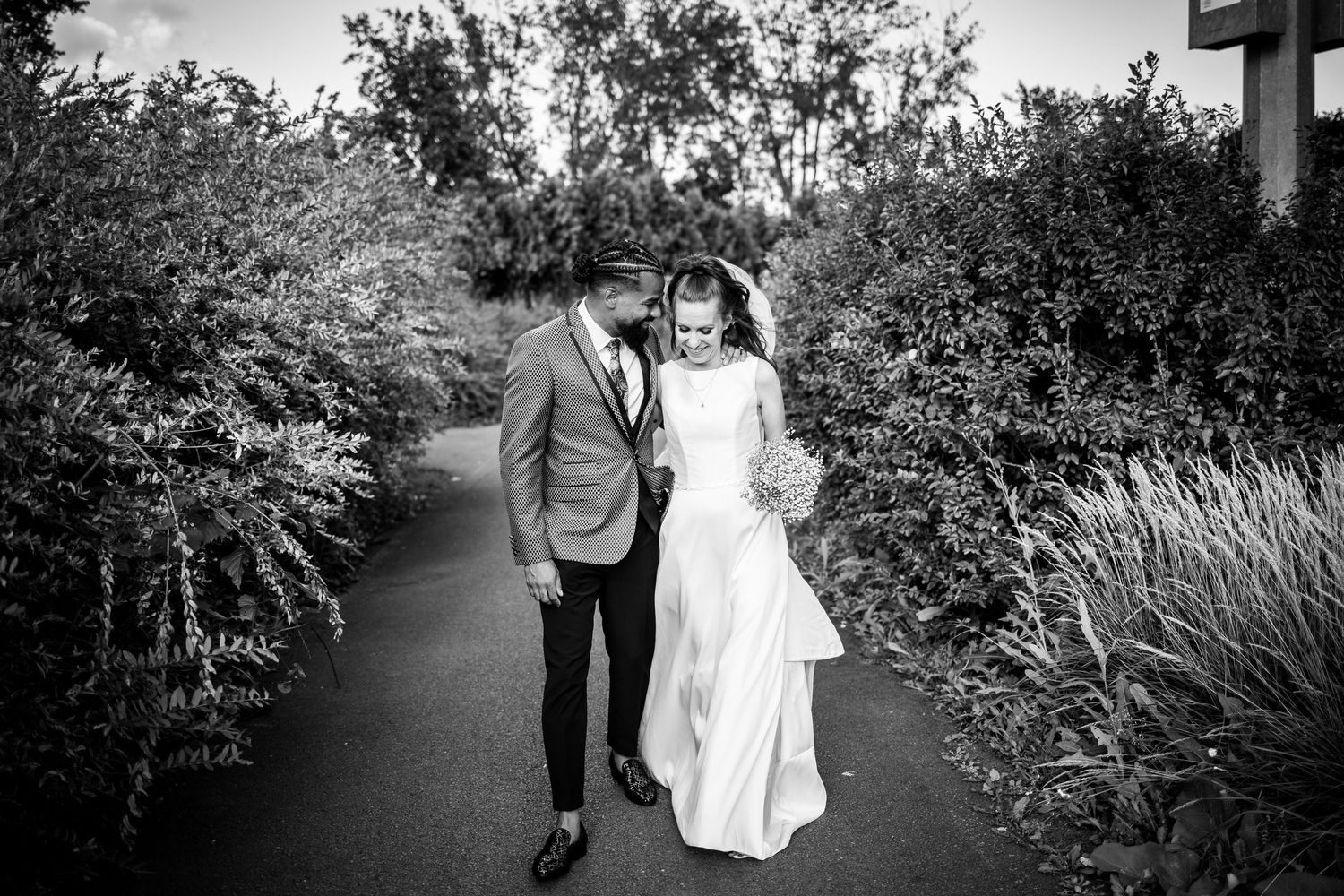 Photo noir et blanc d'un couple de nouveaux mariés se promenant ensemble dans les jardins de la Plaza Rive-Sud, dans la ville de La Prairie.