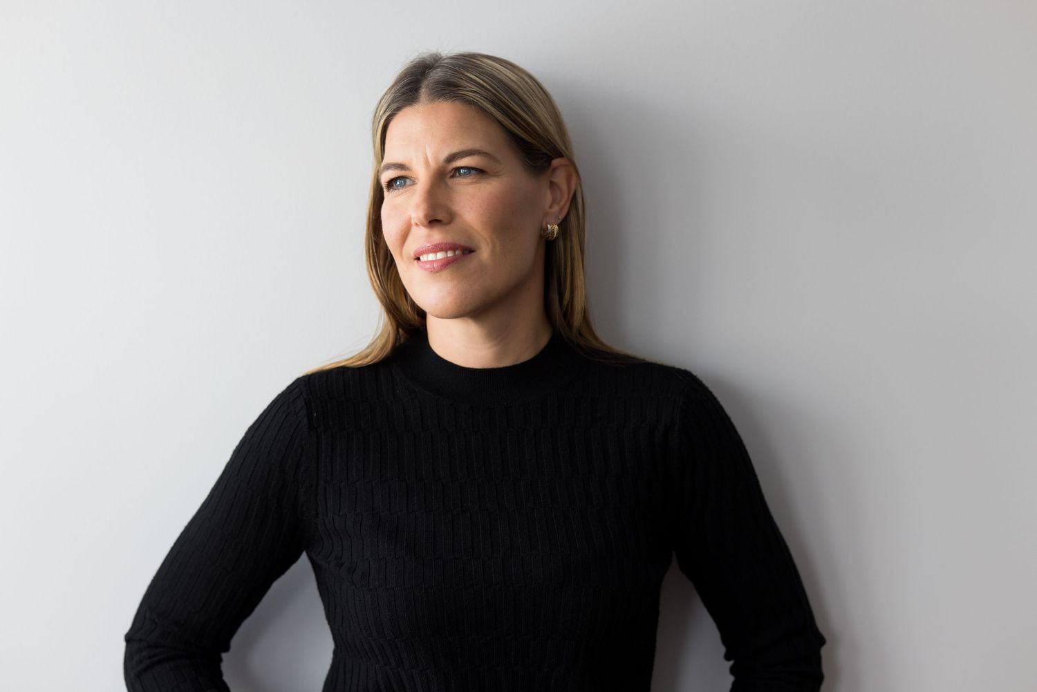 Portrait professionnel d'une femme entrepreneure sur fond gris neutre. Photo prise en lumière naturelle.
