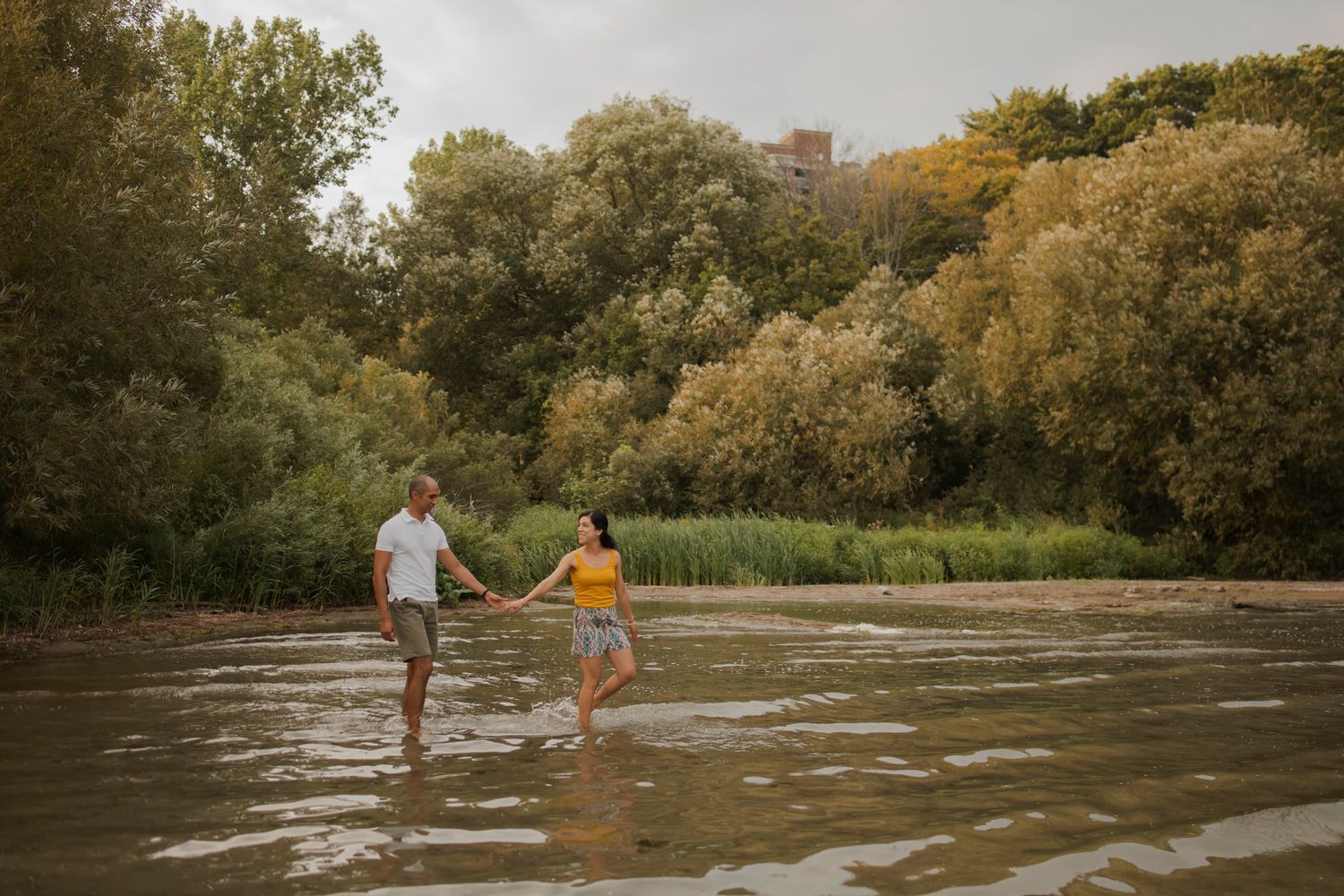 Couple walks through the shallow water at a Lake Ontario Park beach cove.