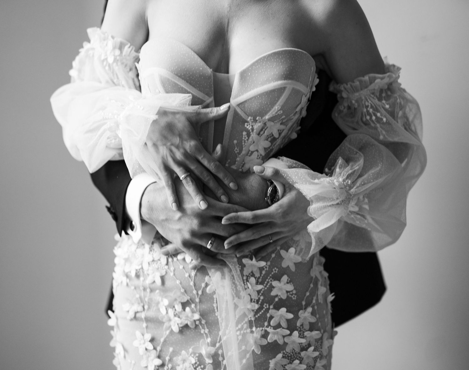 Black and white intimate portrait of couple embracing in formal wedding attire.
