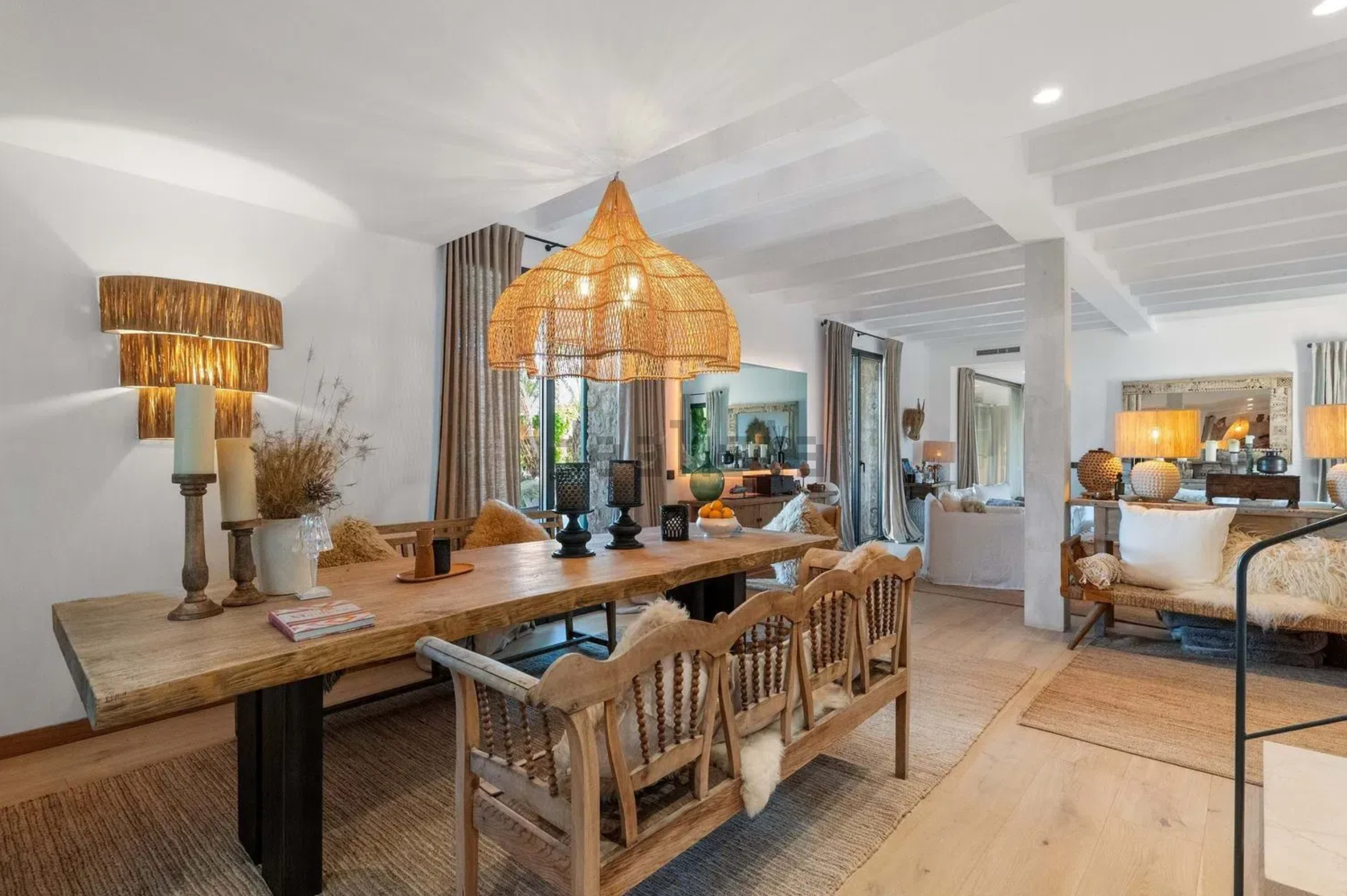 Modern white interior hallway with wooden furniture, pendant lighting and coastal decor elements.