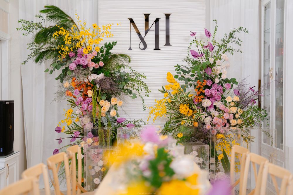 Elegant wedding table setting with vibrant floral arrangements and monogram MH backdrop.