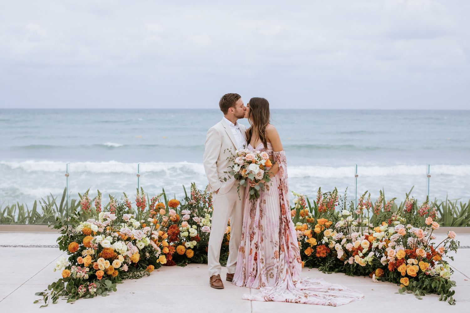 Newlyweds sharing a kiss in front of a floral circle on the ground during their wedding ceremony, surrounded by love and beauty