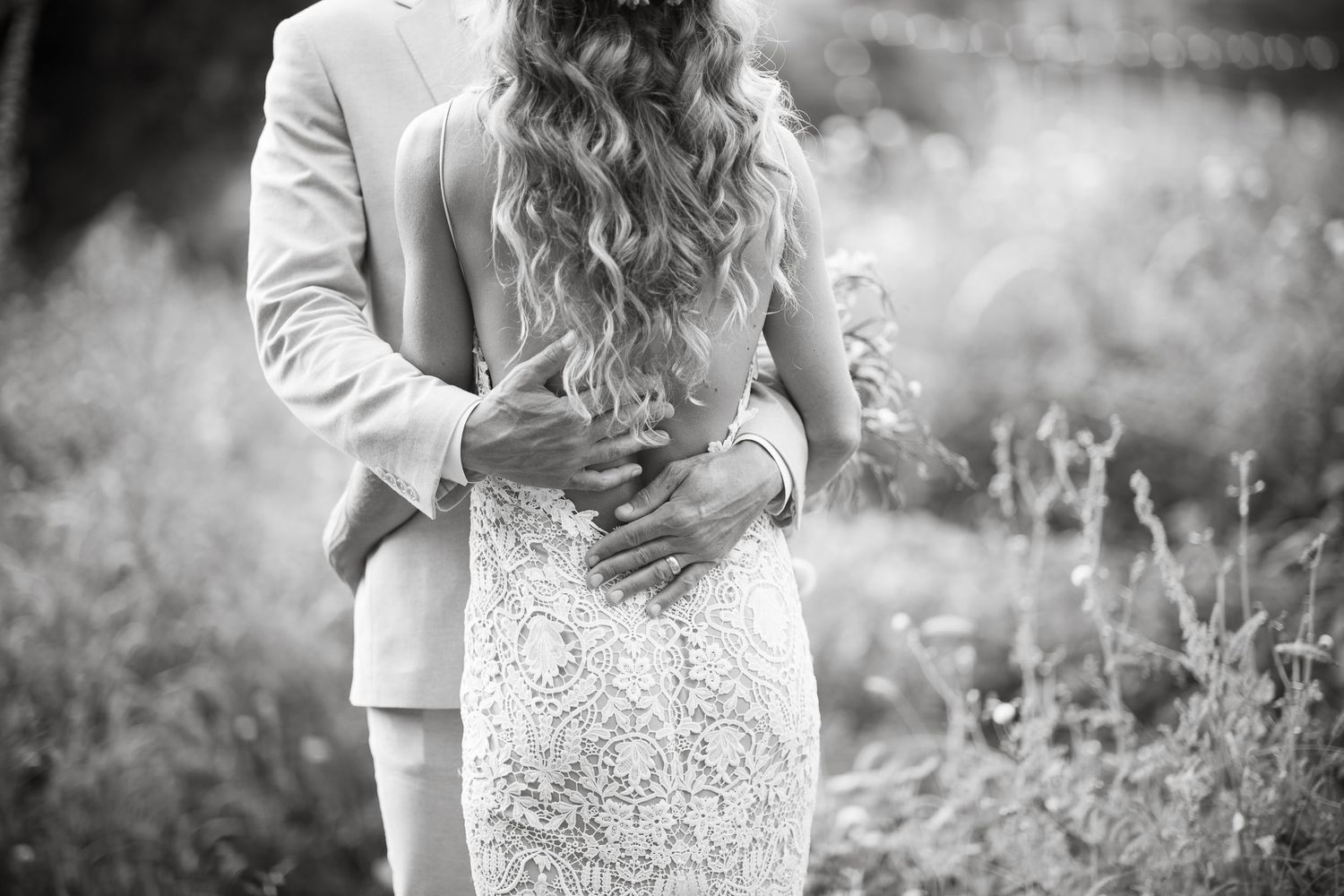Black and white wedding portrait showing romantic embrace between couple in elegant attire.