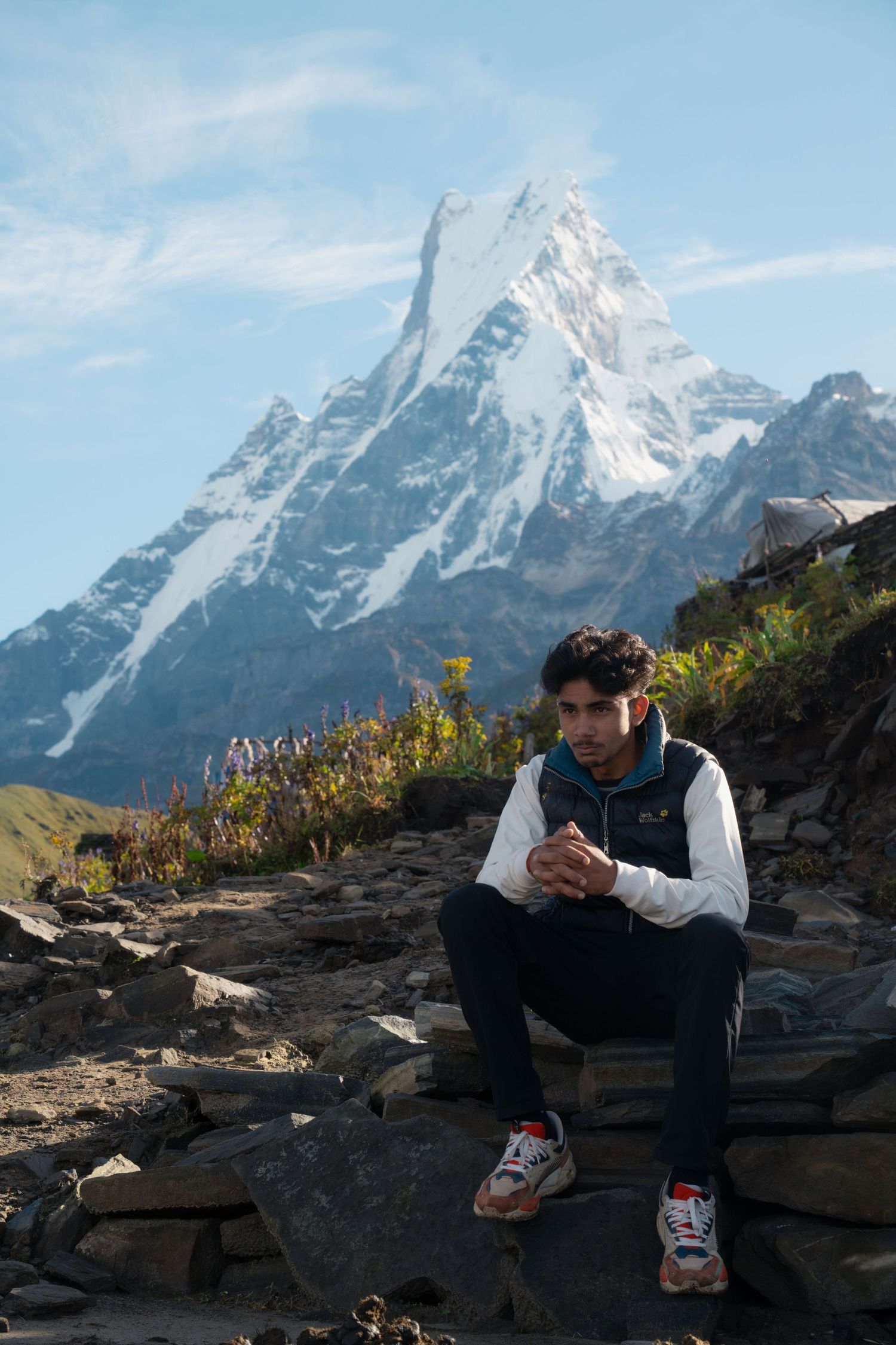 Snow-capped Himalayan peaks tower above rocky terrain in bright daylight.