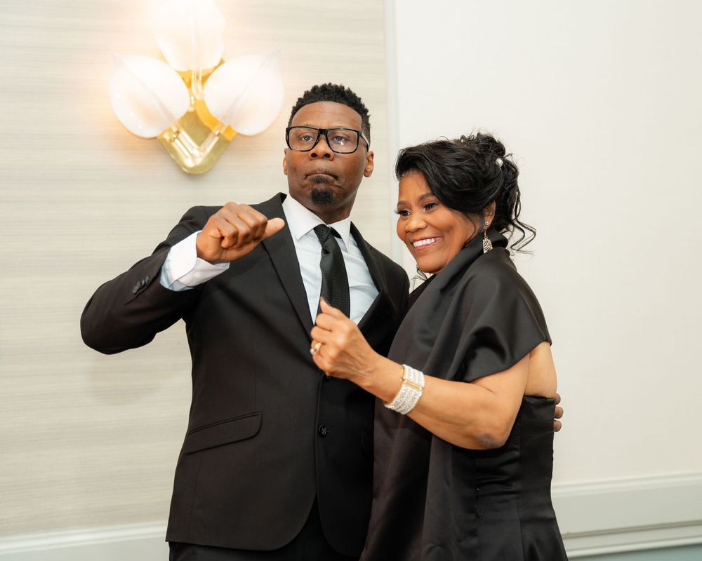 Two people in formal attire strike a fun pose during an evening celebration.