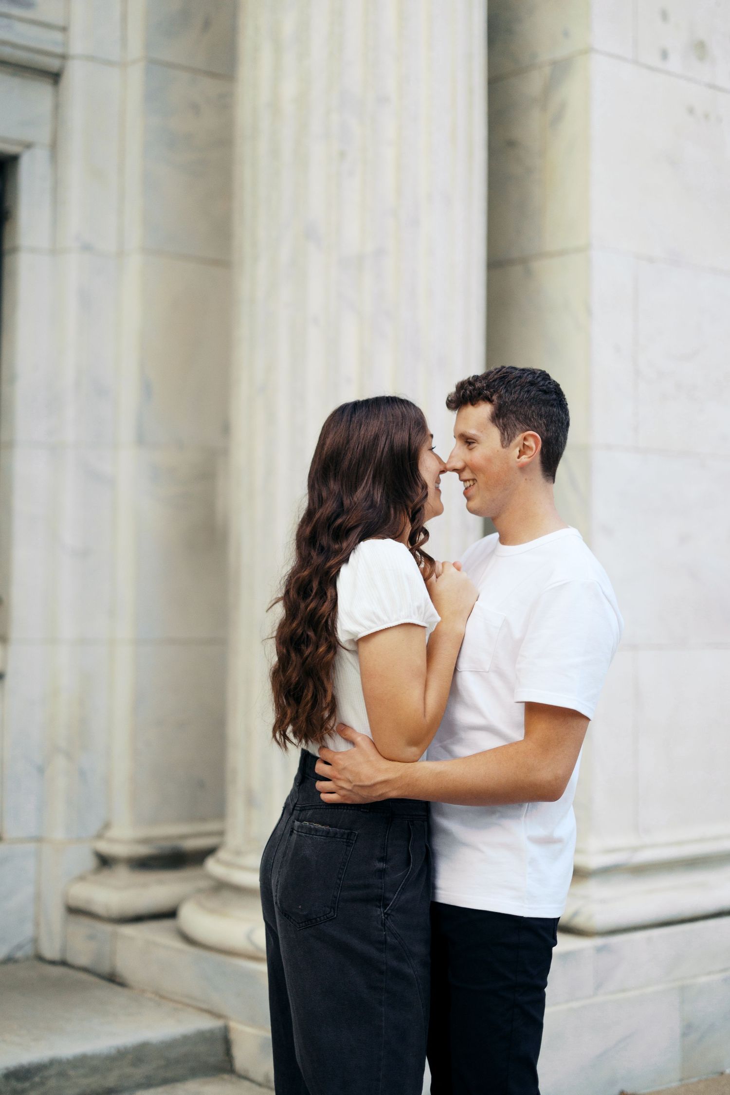 A romantic couple embraces while standing in calm ocean waters at sunset, creating a dreamy seaside moment.